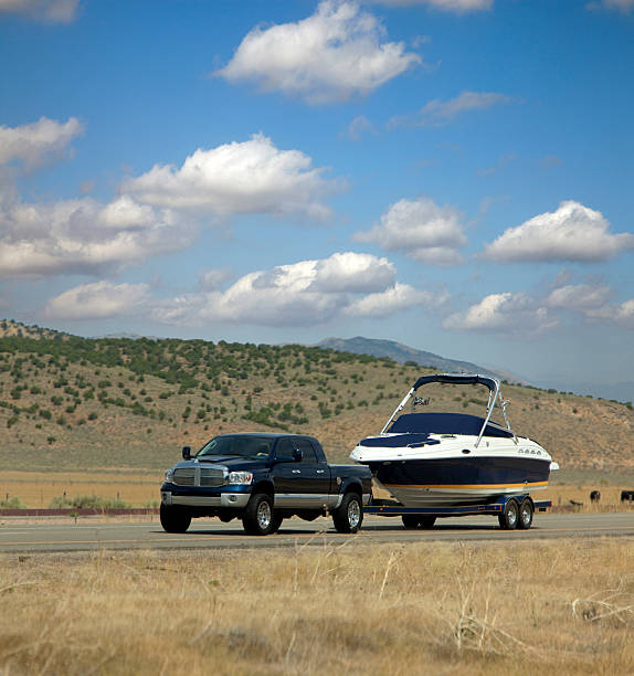 a truck tows a boat down a scenic road.